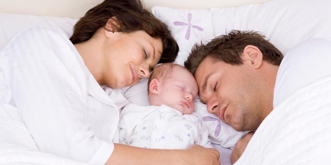 newborn baby sleeping in bed with parents