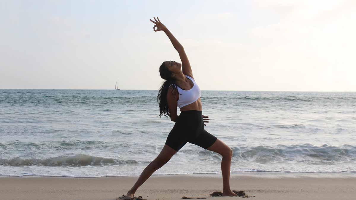 couple practising yoga poses sitting on beach by sea Stock Photo - Alamy