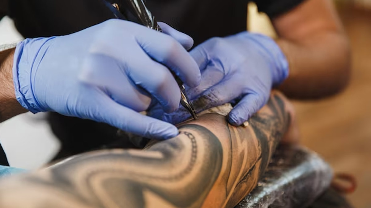 Premium Photo  The tattoo artist in blue gloves cleaning the newly  completed tattoo on a mans leg