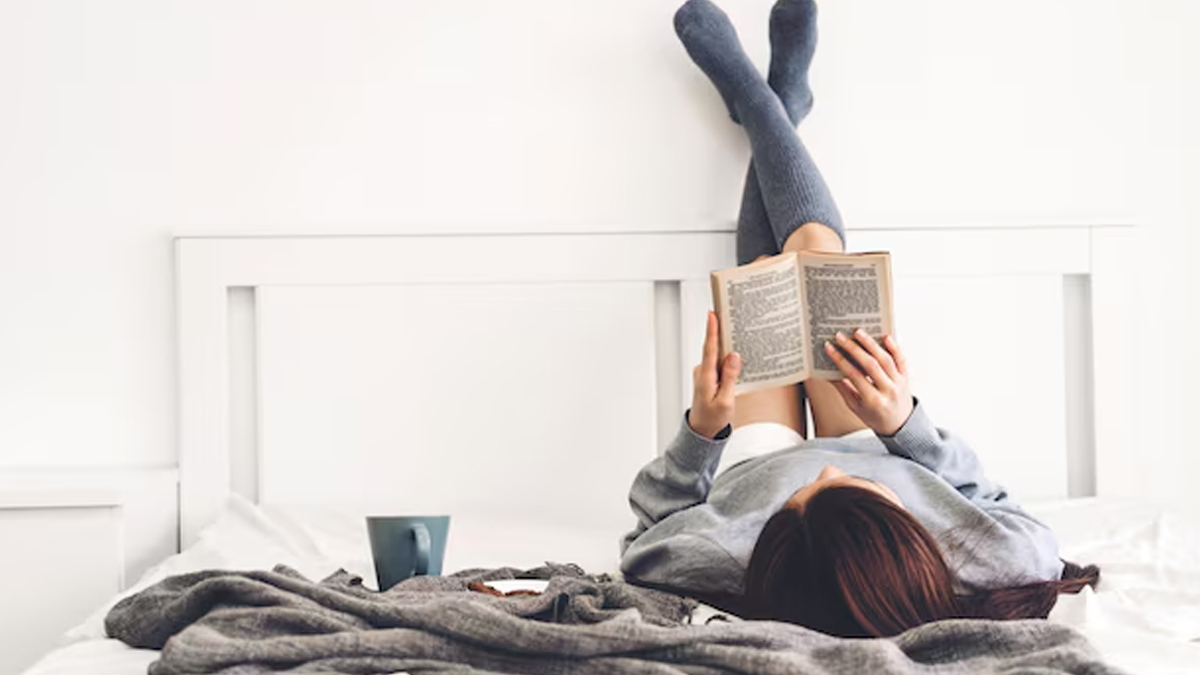person-reading-book-on-bed